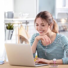 Happy young woman working on laptop at home